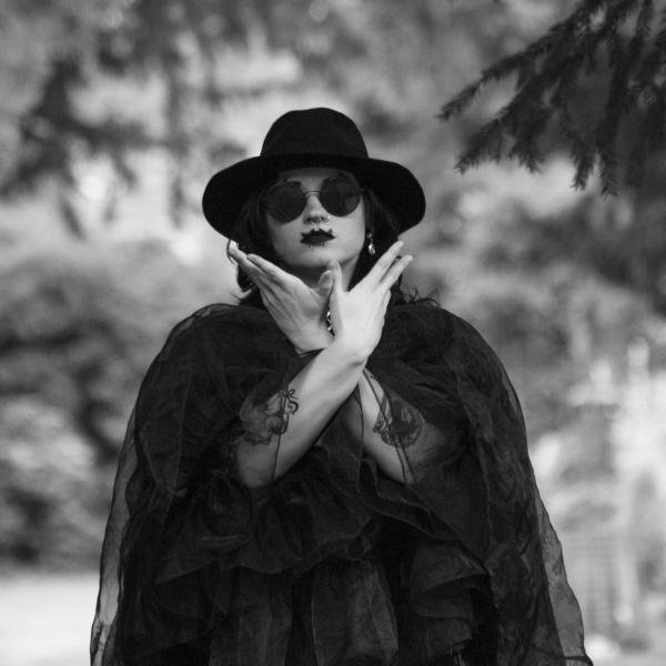 Portraitfoto von Lin Eigelshoven mit verschränkten Armen, Sonnenbrille und Hut. Bild: © privat