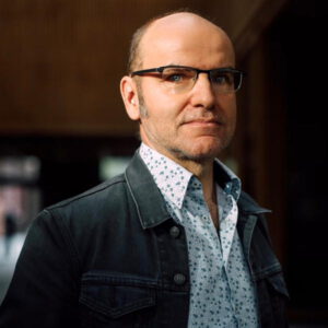 Der Comic-Zeichner Lewis Trondheim mit gemustertem Hemd, dunkler Jacke und Brille. Bild: © Chloe Vollmer